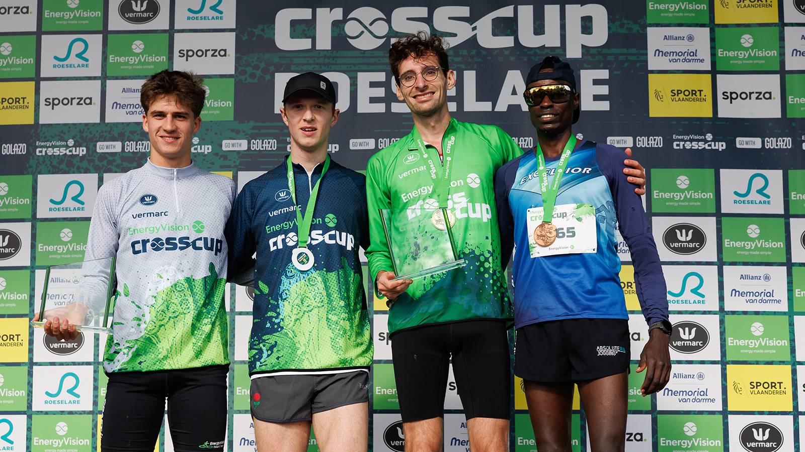 Belgian Mathis Lievens, Great Britain's James Kingston, Belgian Guillaume Grimard and Burundi's Patrick Nimubona celebrate on the podium after the men's race at the CrossCup cross country running athletics event in Roeselare, the second and stage of the CrossCup competition, Sunday 26 October 2025. BELGA PHOTO KURT DESPLENTER